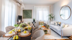 A modern living room with a dining area, featuring a sofa, chairs, a coffee table, and a TV. - The City Terrace Apartment: smart 2 bedrooms in Lucca (Lucca)