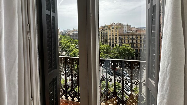 Un balcon orné de balustrades en fer forgé, offrant une vue sur les bâtiments de la ville.