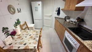 Une cuisine de taille réduite, équipée d’un réfrigérateur, d’une cuisinière et d’un plan de travail.