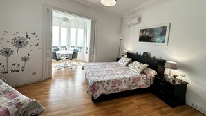 Une chambre avec deux lits, un coin repas avec une table et des chaises, et une grande fenêtre.