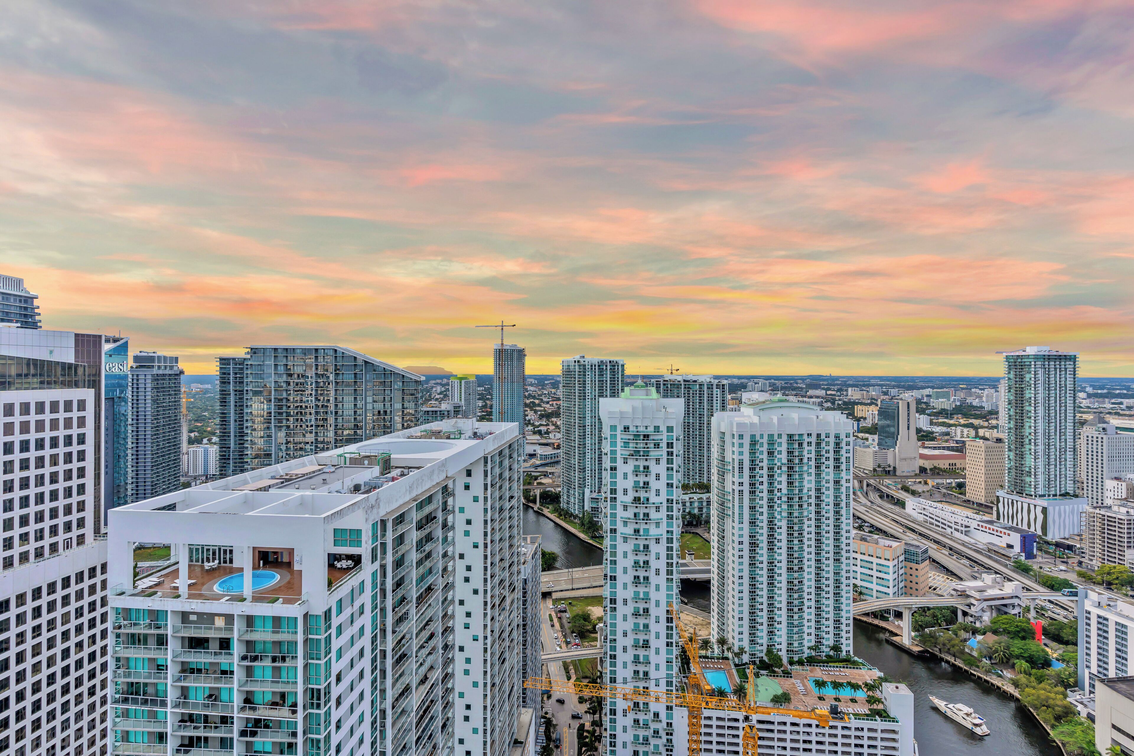 A high-rise building with multiple floors, a rooftop pool, and a view of a river and surrounding cityscape.