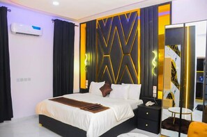 A modern hotel room with a large bed, a bedside table, a mirror, and a wardrobe. - Republican City Apartment (Awka)