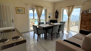 A spacious living area with a dining table, a sofa, and a kitchen with a stove.