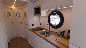 Una cocina compacta con fregadero, microondas y ventana con vista circular.