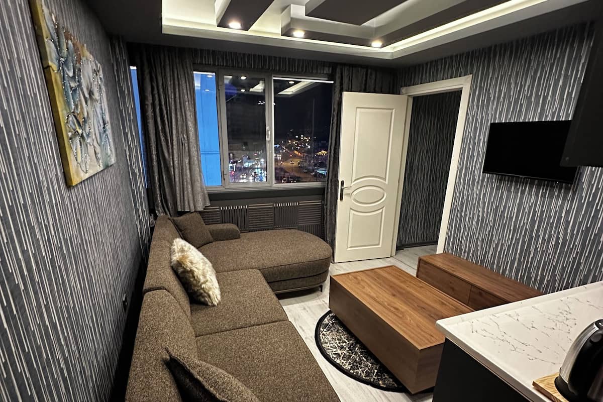 A modern living room with a sectional sofa, a wooden coffee table, and a TV mounted on the wall.