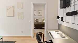 A modern bedroom with a bed, a desk with a lamp, and artwork on the walls. - Laia Deluxe Terrace Apartment (Barcelona)