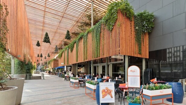 An outdoor dining area with wooden slats and greenery, tables, and chairs. - Laia Deluxe Terrace Apartment (Barcelona)