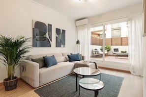 A modern living room with a sofa, a coffee table, and a large window with curtains.