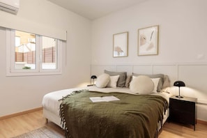 A bedroom with a bed, bedside tables, a window, and wall art.