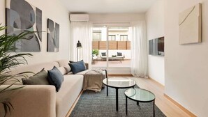 A modern living room with a beige sofa, a glass coffee table, and abstract wall art. - Laia Deluxe Terrace Apartment (Barcelona)