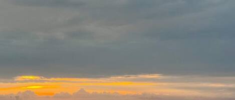 A sunset over the ocean with a distant ship and a small buoy.