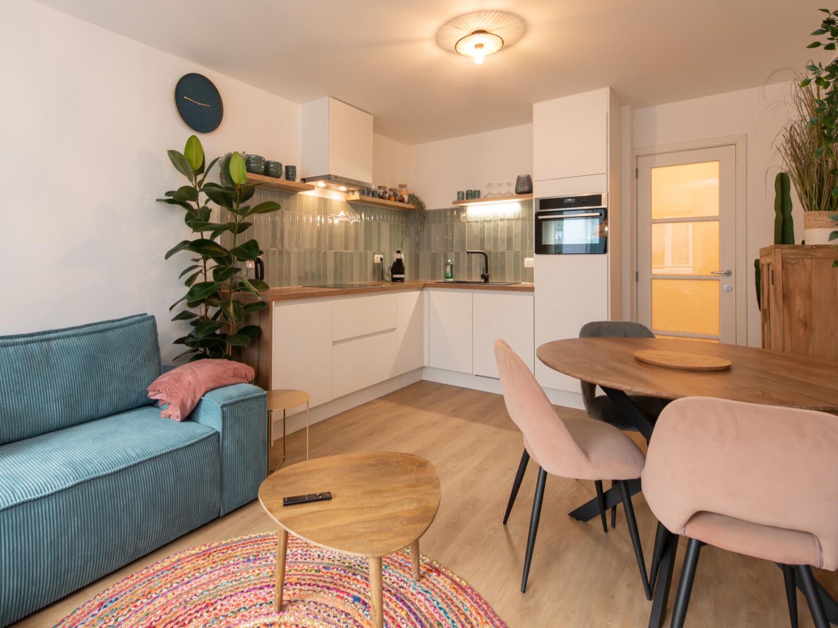 A modern apartment with a kitchenette, a sofa, a dining table, and a coffee table.