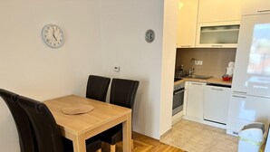 A compact kitchen with white cabinets, a built-in oven, and a refrigerator. - Air Urban 4-room apartment, balcony, parking, air-conditioned and fully equipped (Sarajevo)