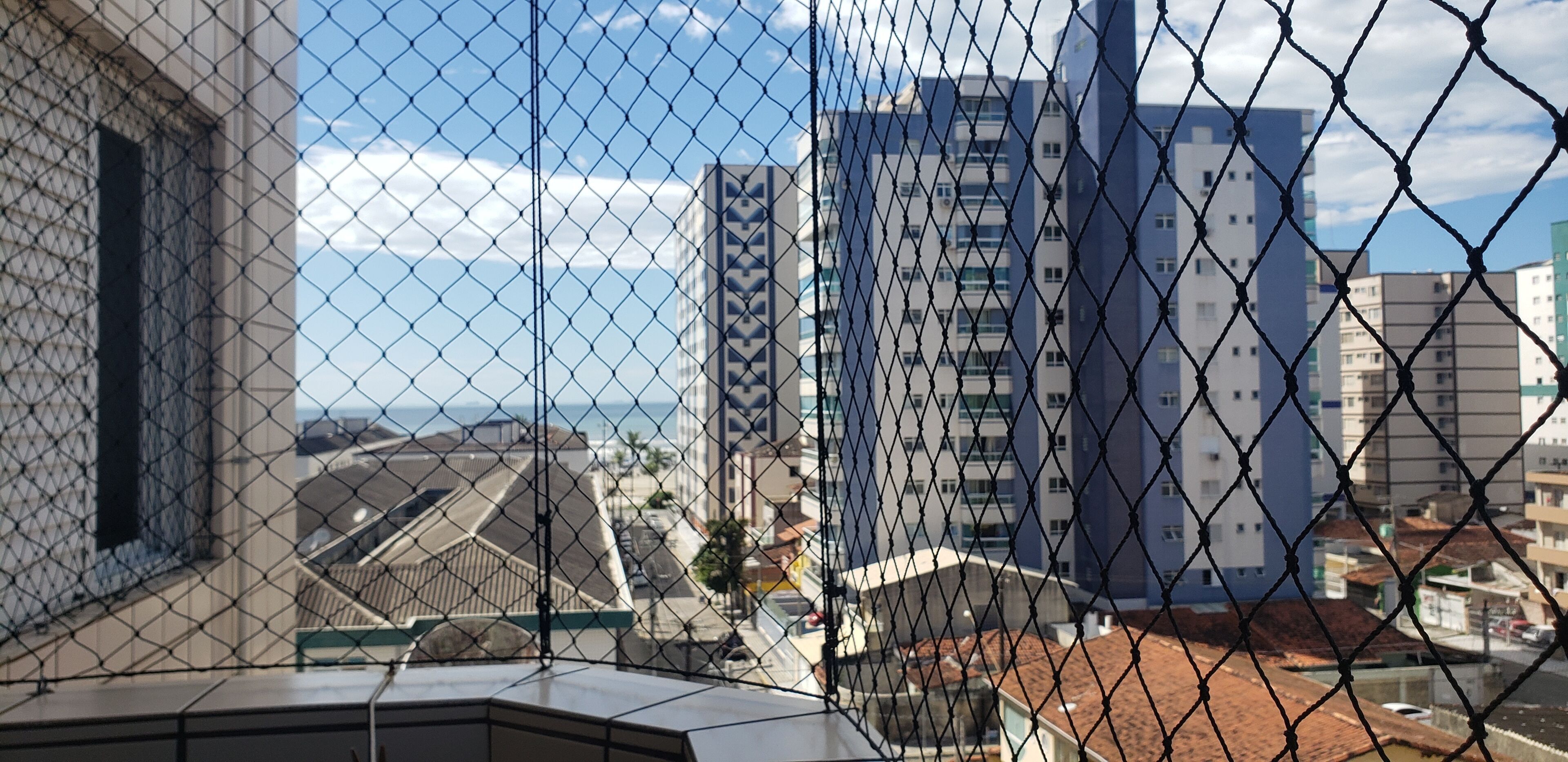 A high-rise building with a chain-link fence in the foreground.