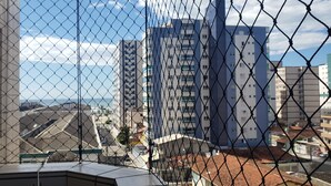 A high-rise building with a chain-link fence in the foreground. - Apartment in KAZAPAZ GUILHERMINA, 73m². Plenty of shops nearby. (Guilhermina Praia Grande)