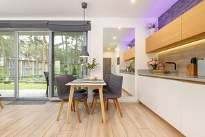 A modern kitchen with a wooden countertop, a dining area with a table and chairs, and a sliding glass door leading to an outdoor space.