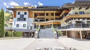 Un hôtel à plusieurs étages doté d’un escalier central, de balcons et d’une enseigne indiquant qu’il fait partie de la chaîne hôtelière des Alpes.