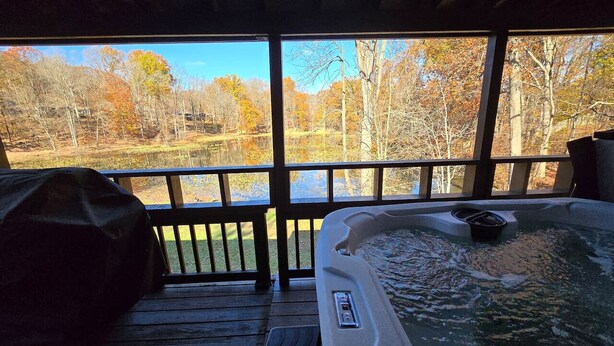 Un jacuzzi en un área exterior techada con vistas a un paisaje boscoso.