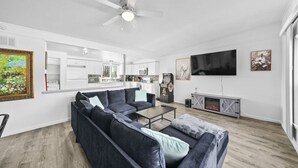 Una sala de estar moderna con un sofá seccional, una mesa de centro, un televisor de pantalla plana y una chimenea.