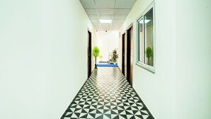 A hallway with a geometric patterned floor, white walls, and doors on both sides. - Hotel Jai Palace & Guest House (Jaipur)