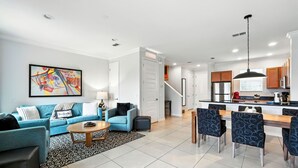 Una sala de estar moderna con un sofá azul, una mesa de centro y un comedor con sillas.