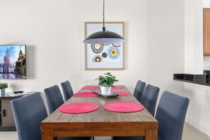 Uma sala de jantar com uma mesa de madeira, seis cadeiras e uma luminária pendente.