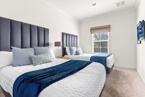 A hotel room with two beds, a large window with blinds, and a wall-mounted sign.