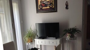 A dining area with a table, chairs, a television, and potted plants.