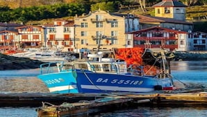 A harbor with boats docked, a building with a bell tower, and a row of colorful houses.