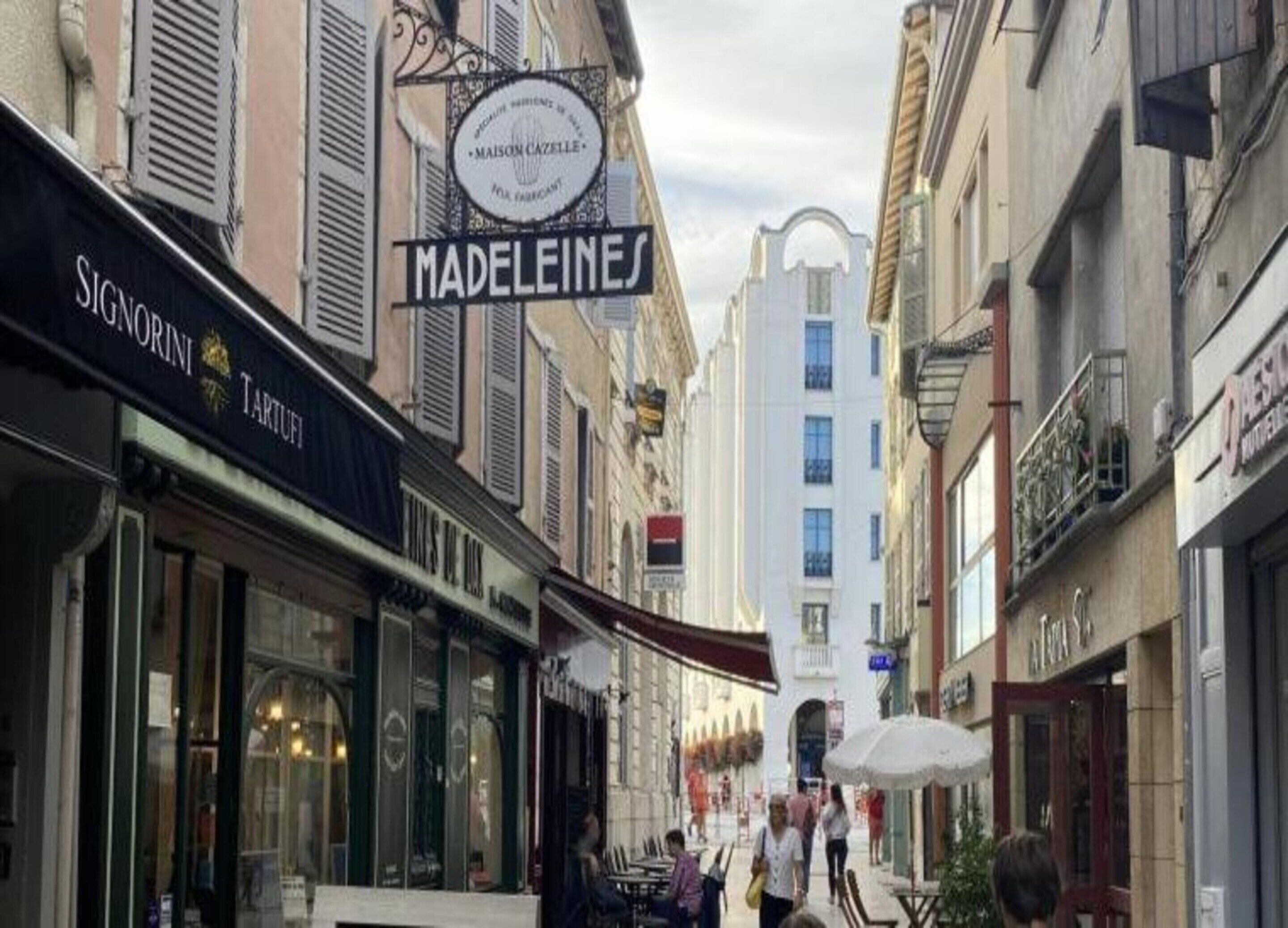 A narrow street with shops, including 'MADELEINE' and 'SIGNORINI TARTUFI'.