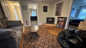 A living room with a fireplace, a coffee table, a sofa, and a bookshelf. - Spacious 4-bedroom house in charming Montreal across from The Gile Flowage (Montreal)