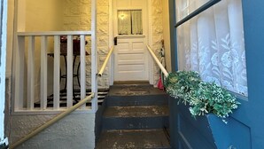 A staircase with a white door at the top, a blue wall with a floral pattern, and a plant on the right. - Spacious 4-bedroom house in charming Montreal across from The Gile Flowage (Montreal)