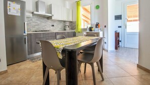 Une cuisine moderne avec un coin repas, comprenant une table avec des chaises, un réfrigérateur et une fenêtre avec des rideaux.