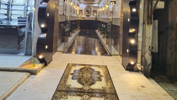 Um saguão de hotel com corredor central, iluminação decorativa e carpete estampado.