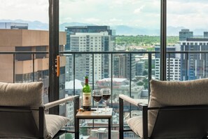 A balcony with two chairs, a table, a bottle of wine, and two wine glasses.