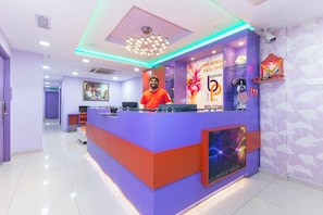 A reception desk with a modern design, featuring a purple and red color scheme, a digital screen, and a 'Welcome' sign. - Hotel O Brickfields Park Hotel (Kuala Lumpur)