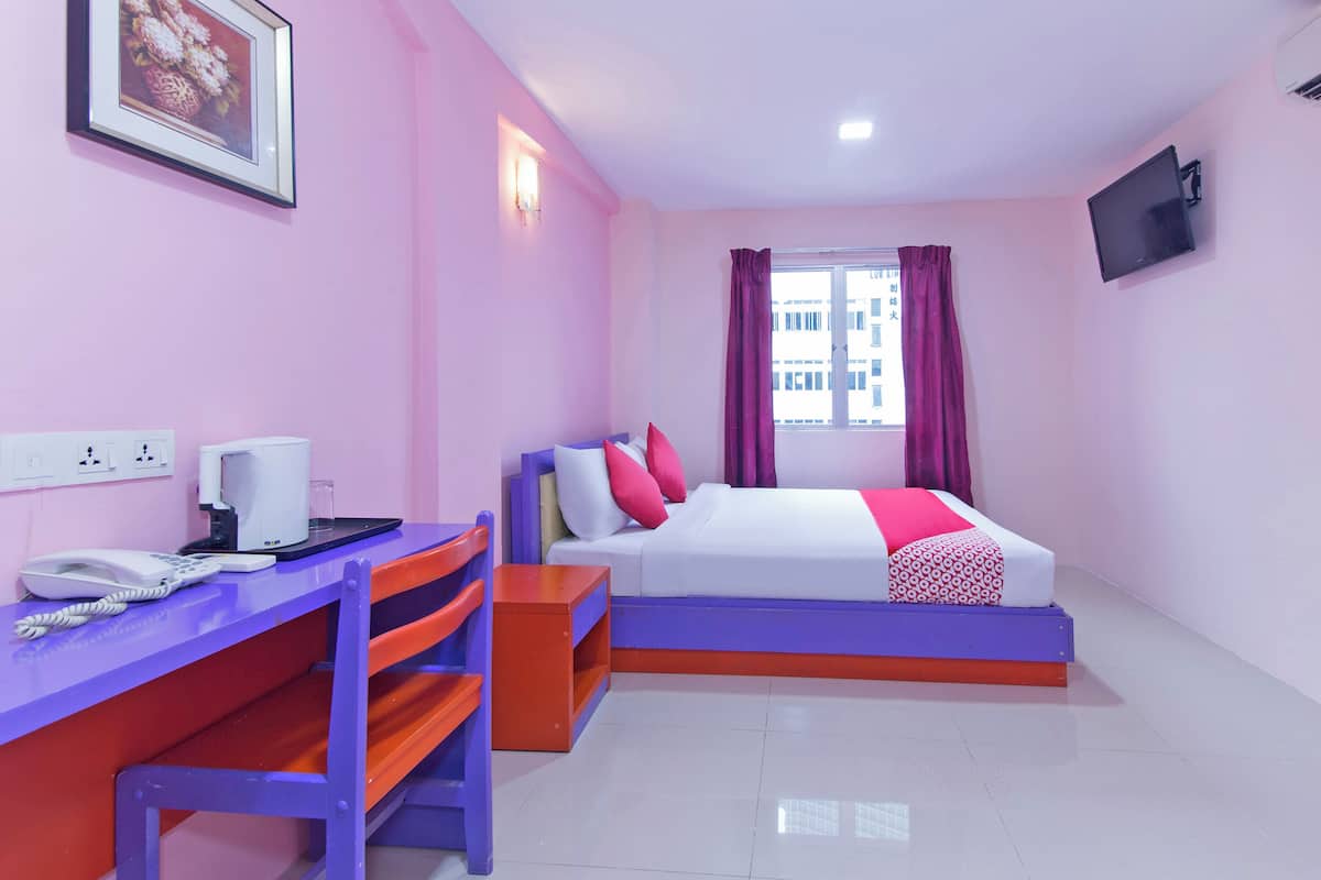 Habitación de hotel con cama, escritorio con teléfono y ventana con cortinas.