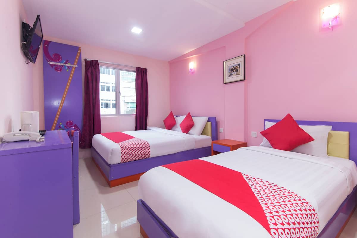 Habitación de hotel con dos camas, un escritorio, un teléfono y una ventana con cortinas.