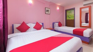 Een hotelkamer met twee bedden, elk voorzien van rode en witte beddengoed, een ingelijste foto aan de muur en een airconditioning.