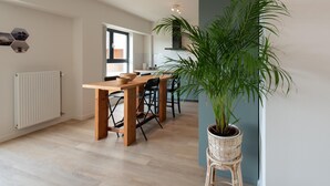 Une cuisine moderne avec un coin repas, des meubles en bois et une grande plante en pot.