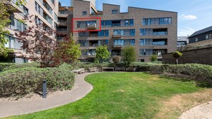 Un immeuble d’appartements moderne doté de nombreux balcons, d’une pelouse bien entretenue et offrant une vue sur un ciel dégagé.