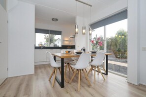 Eine moderne Küche mit Essbereich, großen Fenstern und Ausblick nach draußen.