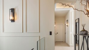 A hallway with a glass railing, a wall-mounted light fixture, and a door at the end. - Airy Suites Athens (Athens)