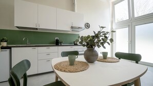 A modern kitchen with white cabinets, a green backsplash, and a dining table with two chairs. - Casa del Falegname · Abete Loft with kitchen · 3 guests (Gaiana di Castel San Pietro Terme)
