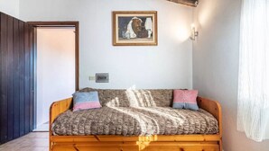 A cozy room with a wooden bed, a framed artwork on the wall, and a door leading to another room.