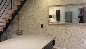 A modern kitchen with a marble backsplash, a wooden staircase, and a large mirror reflecting the room. - Residence "La Menuiserie" 8 guests, spa sauna (2) (GÉRARDMER)