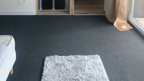 A bedroom with a sliding door leading to a bathroom, a white radiator, a fluffy rug, and a wooden floor. - Residence "La Menuiserie" 8 guests, spa sauna (2) (GÉRARDMER)