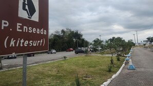 Señal para P. Enseada (kitesurf) con un icono de kitesurf, una carretera con coches y una zona verde con árboles.