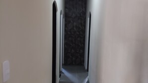 Un pasillo estrecho con un papel tapiz decorativo, un accesorio de iluminación al final y una puerta a la izquierda.