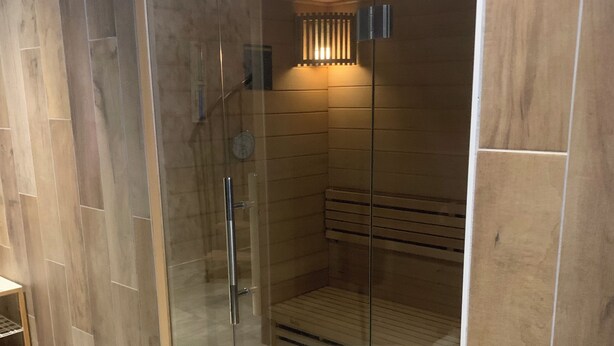 Eine moderne Duschkabine mit Glastür, Holzvertäfelung an den Wänden und einer integrierten Sitzbank.